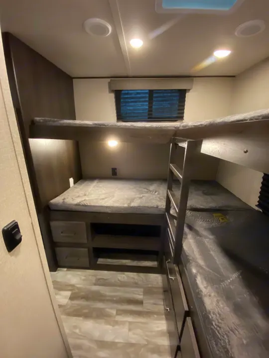Modern RV rental interior with sleek gray bunk beds, bright lighting, and a clean, spacious living area.. Grand Design Transcend Xplor 2022