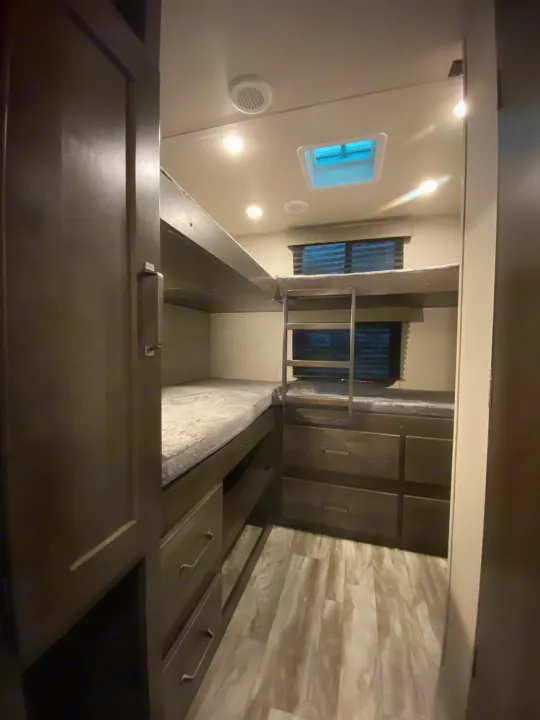 RV rental: Inside a cozy RV, stacked bunk beds with safety rail, window, and storage drawers/cabinets.. Grand Design Transcend Xplor 2022