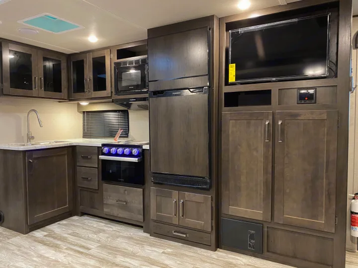 Modern RV rental interior featuring a full kitchen with appliances, entertainment system, and ample storage cabinets.. Grand Design Transcend Xplor 2022