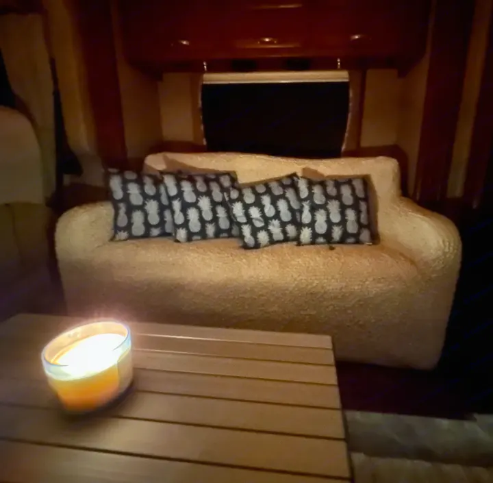 Cozy RV rental living space: sofa with pineapple pillows, warm candle on wooden table for a relaxing ambiance.. Thor Challenger 2015