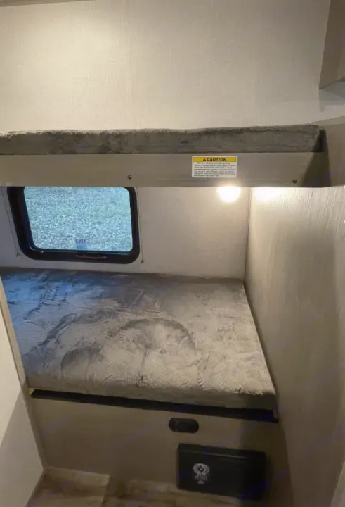 Cozy bunk beds with plush grey mattresses fill this RV rental, offering a window and reading lights for comfortable travel.. Other Other 2021