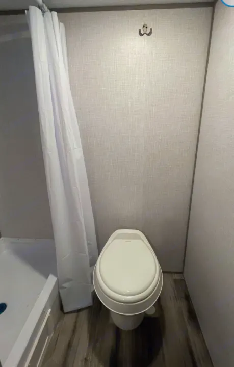 This RV rental features a practical bathroom with a white toilet, shower stall, and light textured walls.. Other Other 2021