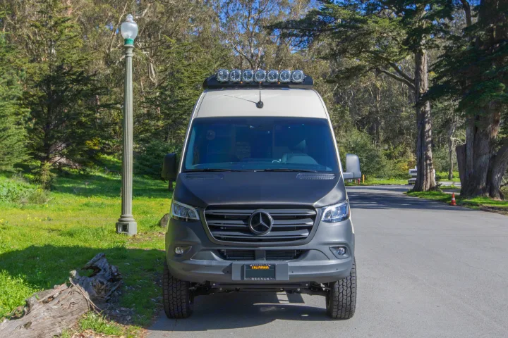 Rugged Mercedes-Benz Sprinter RV rental with off-road tires and roof light bar, parked outdoors.. Other Revel 2023