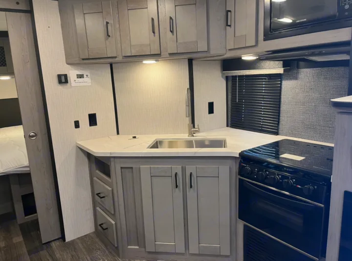 Well-equipped RV kitchen for your next rv rental. Includes sink, stove, microwave, and ample storage cabinets.. Heartland RVs Mallard 2021