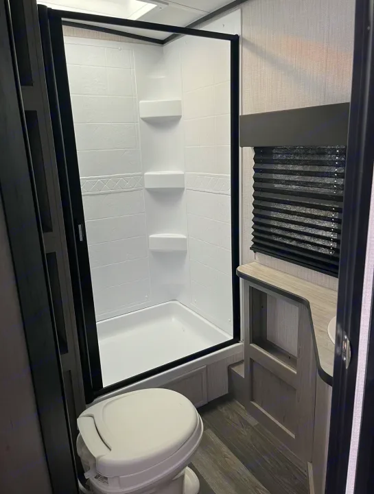 This RV rental features a clean, functional bathroom with a glass shower, toilet, and vanity sink.. Heartland RVs Mallard 2021