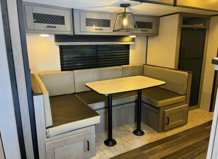 This RV rental features a modern dinette with U-shaped seating, a table, and overhead storage for comfortable dining.. Heartland RVs Mallard 2021