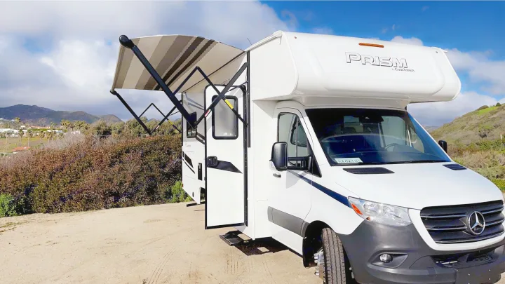 White Class C Prism RV rental, based on Mercedes-Benz Sprinter, parked with awning extended for outdoor comfort.. Coachmen Prism 2023