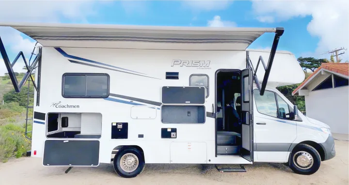 This white Coachmen Prism RV rental, with open storage compartments and an extended awning, is ready for adventure.. Coachmen Prism 2023