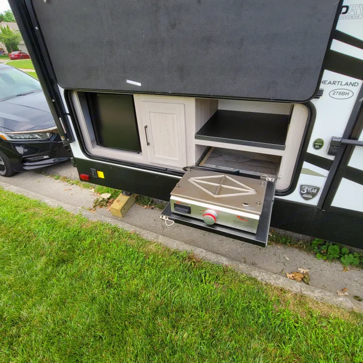 RV rental's outdoor kitchen, featuring a Heartland 278BH and Suburban Elite Series griddle, perfect for camp cooking.. Heartland RVs Sundance Ultra Lite 2022