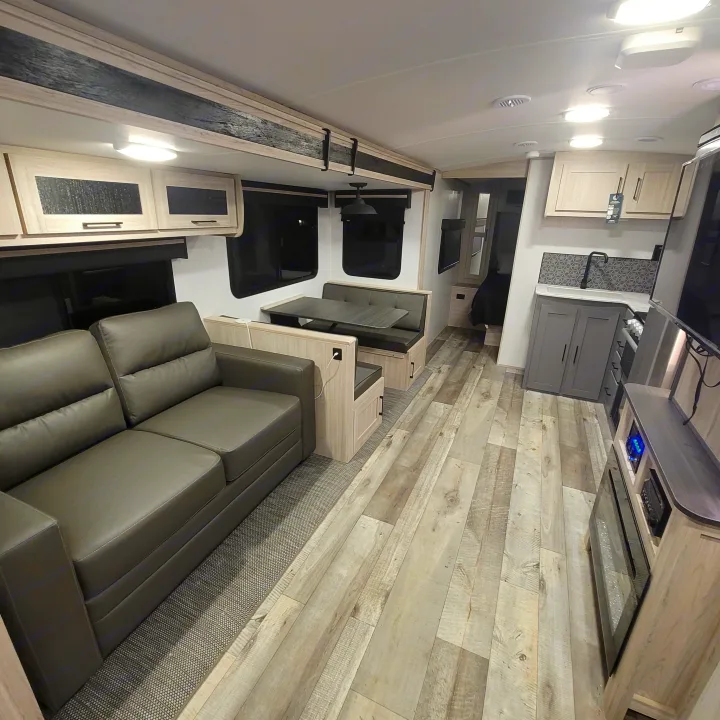 Spacious RV rental interior with modern kitchen, dining booth, sofa, and light wood flooring.. Heartland RVs Sundance Ultra Lite 2022