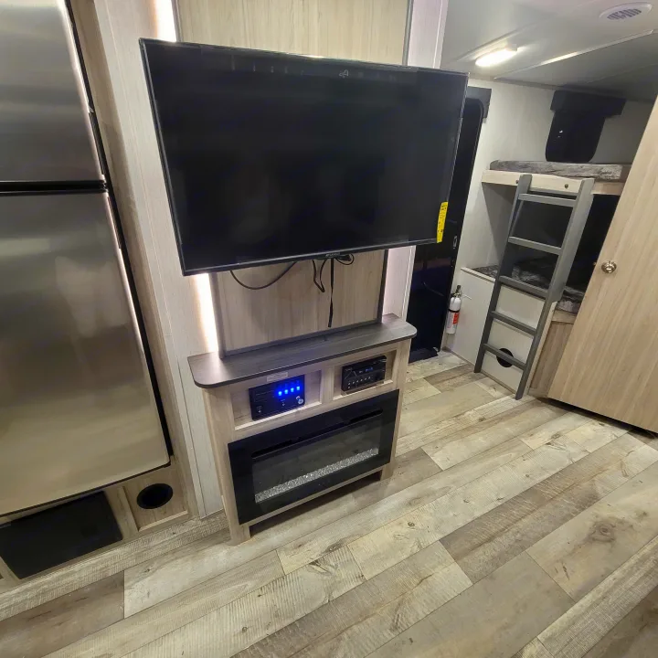 RV rental with a sleek entertainment center, featuring a flat-screen TV, electric fireplace, and control panel for your comfort.. Heartland RVs Sundance Ultra Lite 2022