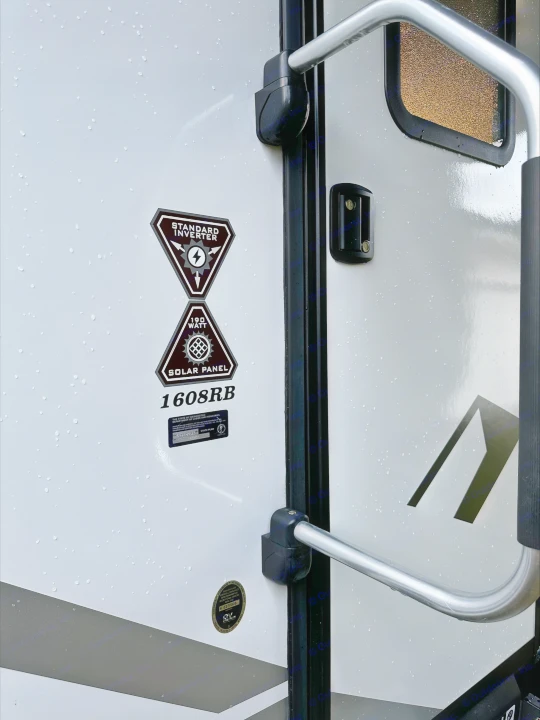 An RV rental's side with specs for inverter and 190W solar panel, model 1608RB, covered in rain.. Dutchmen Coleman Rubicon 2021