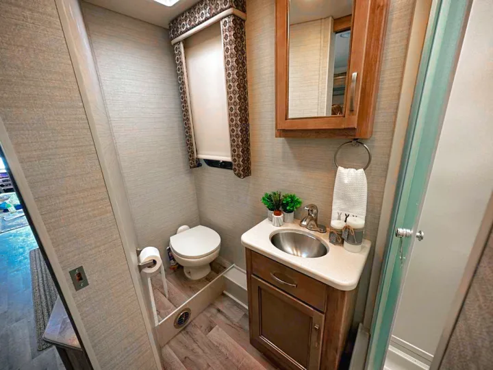 Compact RV rental bathroom with toilet, sink vanity, mirror cabinet, and shower stall shown. Ideal for your next adventure.. Jayco Precept 2019