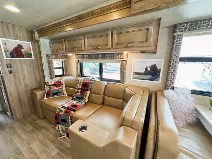 Cozy RV rental living space featuring a large sectional sofa, nature-themed decor with bear art, and bright windows.. Jayco Precept 2019