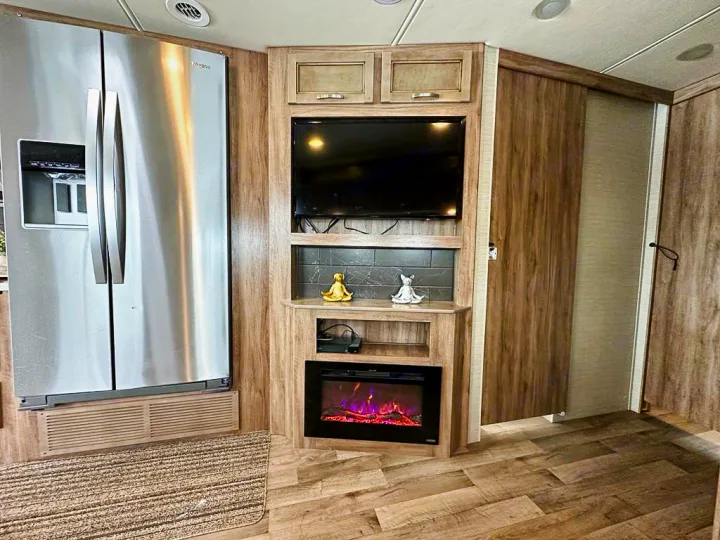 Modern RV rental interior featuring a stainless steel fridge, TV, and cozy electric fireplace.. Jayco Precept 2019