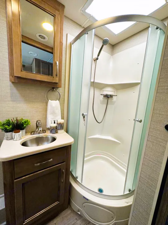 Experience comfort in this compact RV rental bathroom, featuring a corner shower, vanity, and mirror cabinet for your travels.. Jayco Precept 2019