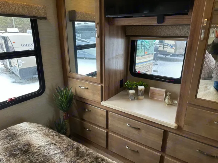 Experience RV rental comfort: a cozy bedroom setup with built-in storage, TV, and views of snowy landscape.. Jayco Precept 2019