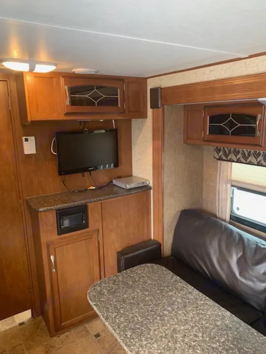 Explore this comfortable RV rental's interior, featuring wooden cabinets, a TV, and a spacious counter for living and dining.. Winnebago Other 2013