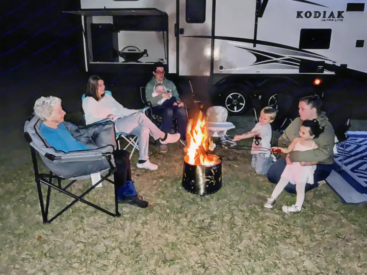 Family bonding around a cozy campfire at night, next to their spacious RV rental. Enjoying outdoor memories.. Dutchmen Kodiak Ultra Lite 2019