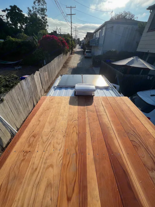 Rooftop deck of an RV rental, with solar panels and a view down a residential alley. Ideal for outdoor adventures.. Dodge Ram Promaster 2500 2017