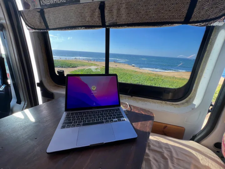 Remote work from an RV rental: a laptop on a table with a stunning beach and ocean view, people enjoying the sun.. Dodge Ram Promaster 2500 2017