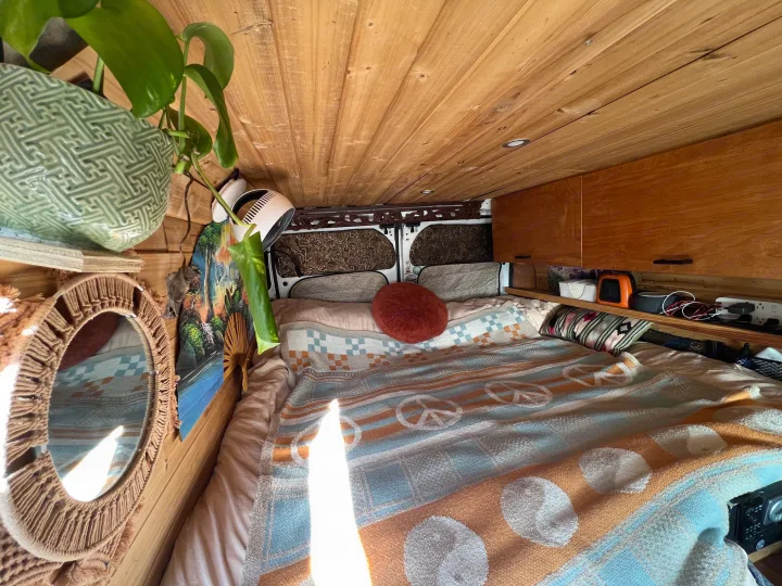 Step inside this cozy rv rental! Features a comfy bed with a peace sign blanket, warm wooden walls, and functional storage.. Dodge Ram Promaster 2500 2017