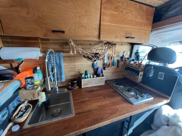 Spacious RV rental kitchen with wood counters, sink, and stove, showcasing practical mobile living features.. Dodge Ram Promaster 2500 2017