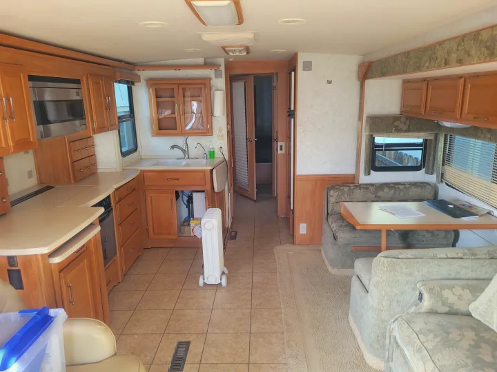 Bright rv rental interior, featuring a well-equipped kitchen, dining booth, and plush seating.. Winnebago Adventurer 2005