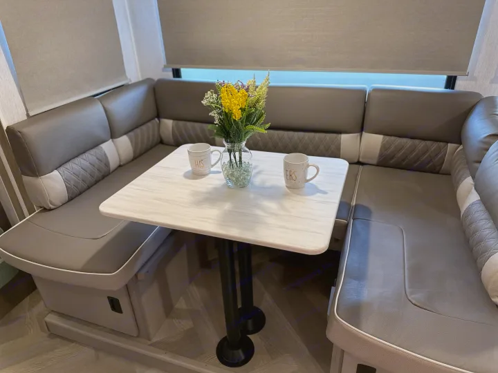 Cozy RV rental dinette with U-shaped booth seating, table, and a floral centerpiece.. Forest River Wildwood X-Lite 2022