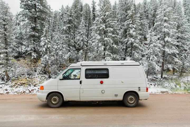 White camper van RV rental parked on a snowy forest road. Ready for your winter adventure.. Volkswagen Eurovan Full Camper 1997