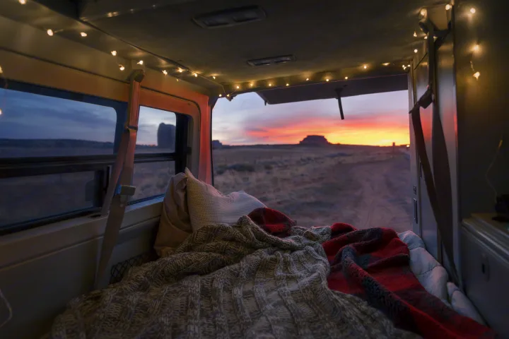Cozy RV rental bed with string lights, looking out to a stunning desert sunset. Perfect for road trip adventures.. Volkswagen Eurovan Full Camper 1997