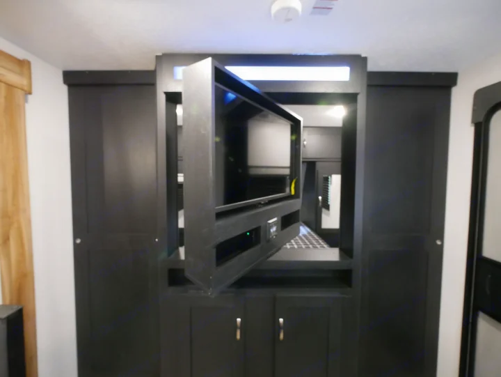 RV rental interior showcasing a practical swivel TV, integrated entertainment system, and sleek storage cabinetry.. Forest River Coachmen Freedom Express Ultra Lite 2022