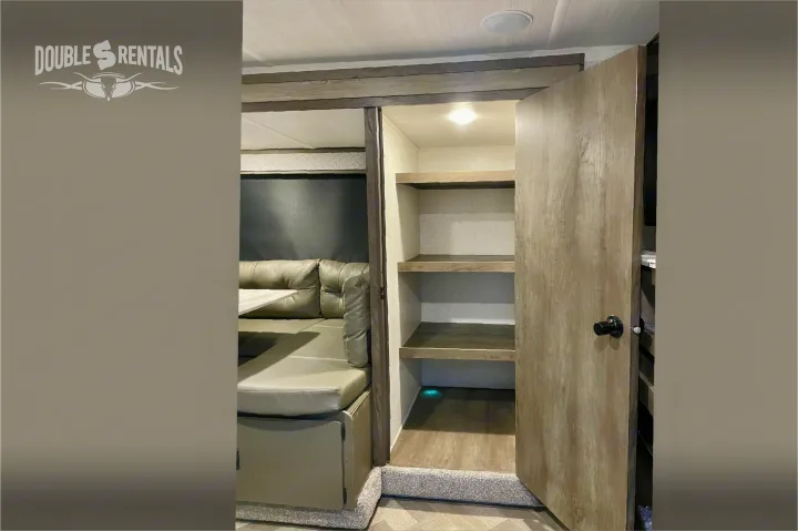 RV rental's functional interior: cozy dinette & accessible pantry with three wooden shelves & accent lighting.. Forest River Wildwood X-Lite 2020