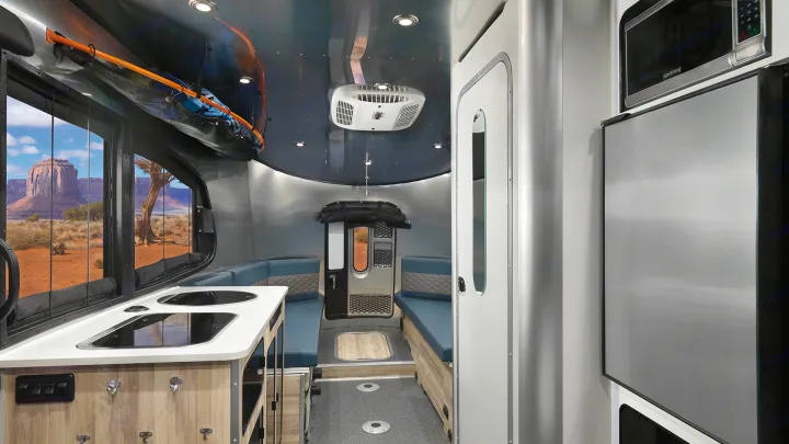 Spacious RV rental interior featuring a modern kitchen, comfortable seating, and large windows with desert landscape views.. Airstream Basecamp 2022
