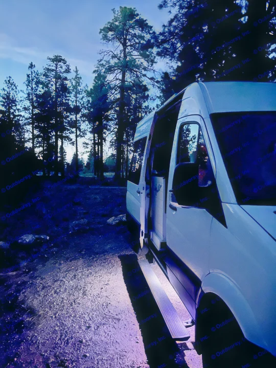 White **RV rental** van parked at night with open door and glowing purple step in a dim forest. Ready for adventure.. Mercedes-Benz Sprinter RV Motorhome Campervan 2016