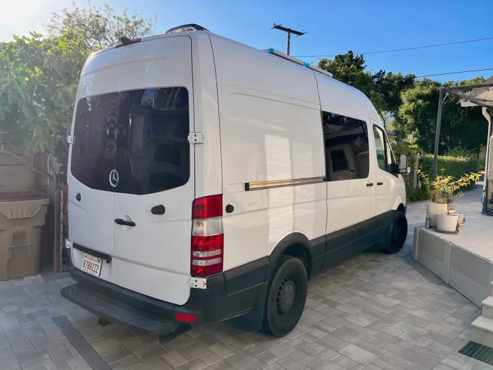 White Mercedes Sprinter camper van with roof unit, likely an RV rental, parked on a paved driveway.. Mercedes-Benz Sprinter RV Motorhome Campervan 2016