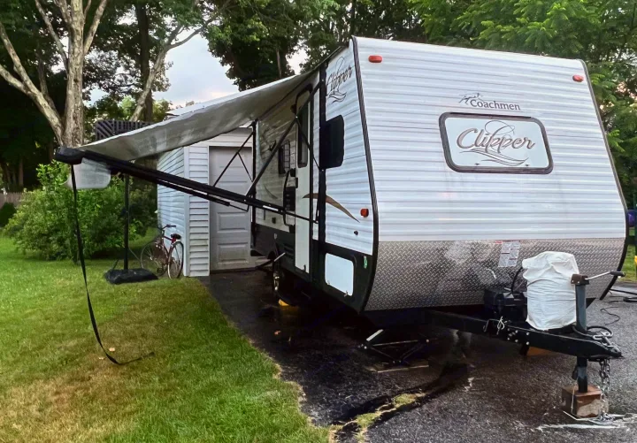 Coachmen Clipper travel trailer with awning extended, parked on a driveway. Perfect for an RV rental getaway!. Coachmen Clipper 2016