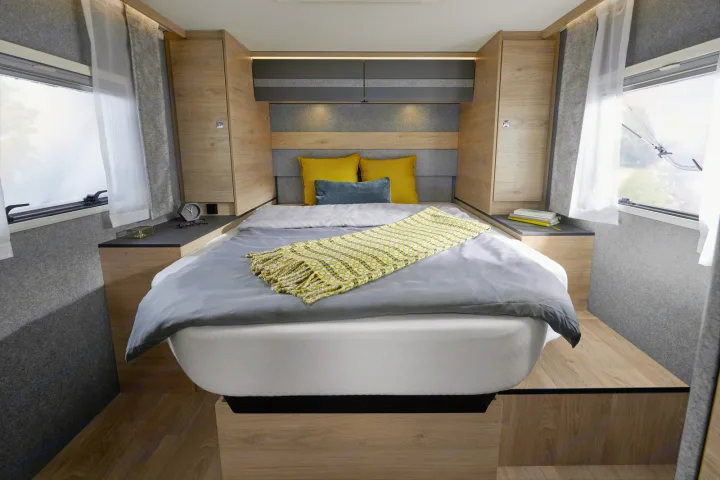 Modern RV rental bedroom with a large bed, nightstands, ambient lighting, and windows for a comfortable journey.. Dethleffs JUST T7052 DBM 2023