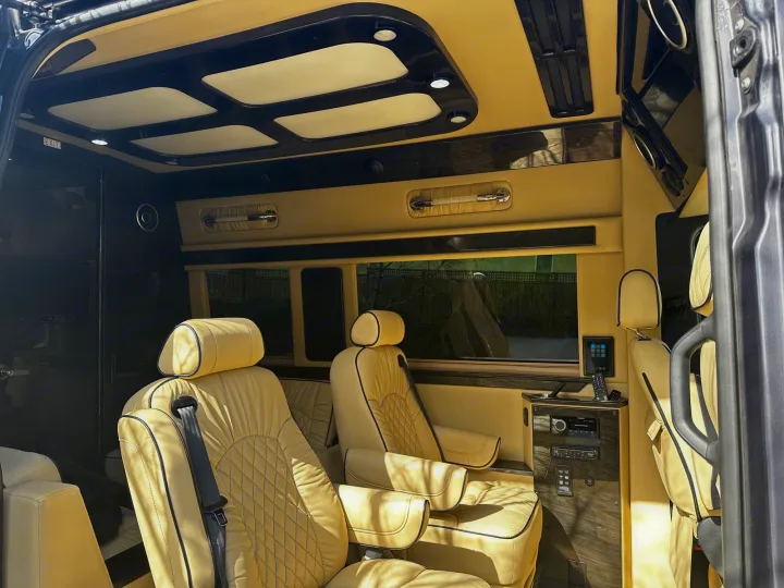Interior of an RV rental, showing luxurious cream quilted leather seats, elegant wood accents, and ceiling lighting.. Ultimate Toys Ultimate Cruiser 2021