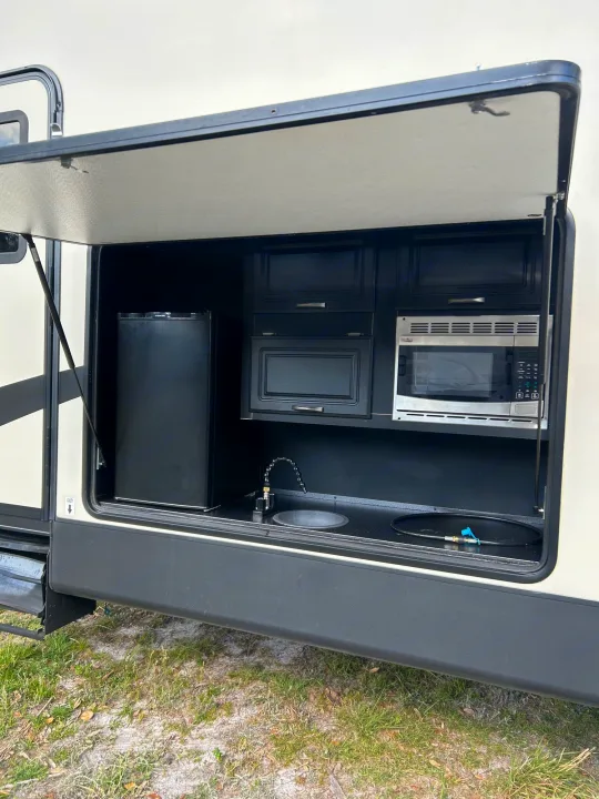 This RV rental features a convenient outdoor kitchen with a mini-fridge, microwave, and sink for easy camping.. Forest River Sandpiper 2018
