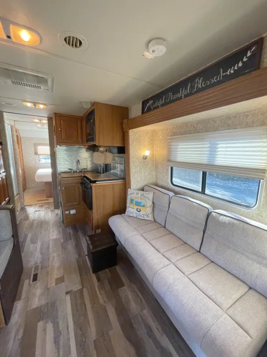 Spacious RV rental interior featuring a cozy sofa, full kitchen, and bedroom view, perfect for your next adventure.. Safari Ivory 2006