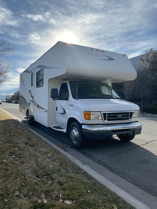 White "Ivory by Safari" RV parked on a street with mountains, ideal for an RV rental adventure.. Safari Ivory 2006