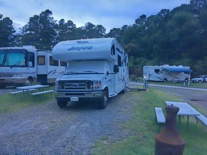 Several RVs, including a Jayco Class C & Class A motorhome, parked in a camp spot at dusk. Ideal for your next RV rental getaway.. Jayco Greyhawk 2014