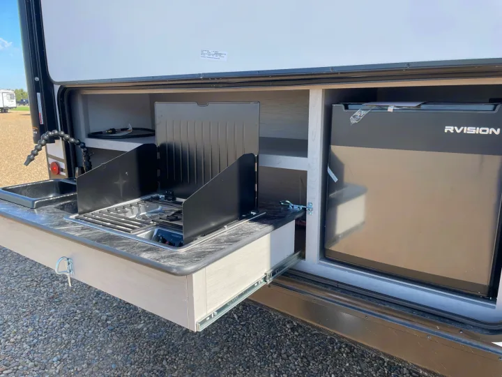 This RV rental features a pull-out outdoor kitchen with a sink, two-burner stove, refrigerator, and storage shelves. Ideal for campsite cooking.. Forest River Tracer 2022