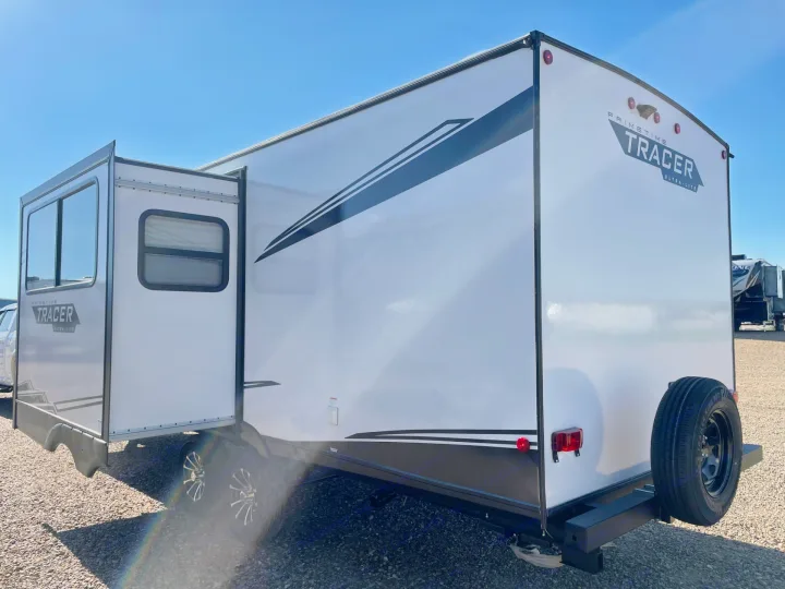 White Primetime Tracer Ultra-Lite travel trailer, ideal for your next RV rental adventure. Slide-out extended, spare tire visible.. Forest River Tracer 2022