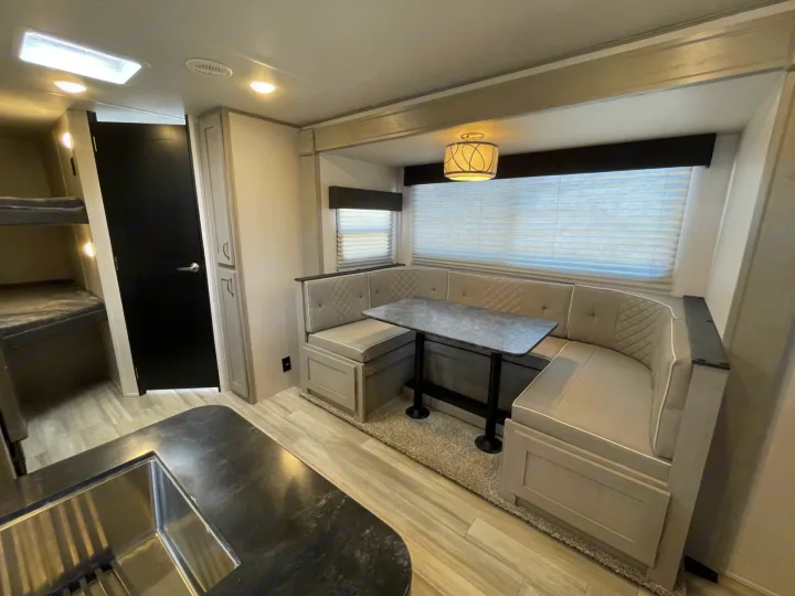 Spacious RV interior featuring a U-shaped dinette, kitchen, and bunk beds, perfect for your next rv rental adventure.. Forest River Tracer 2022