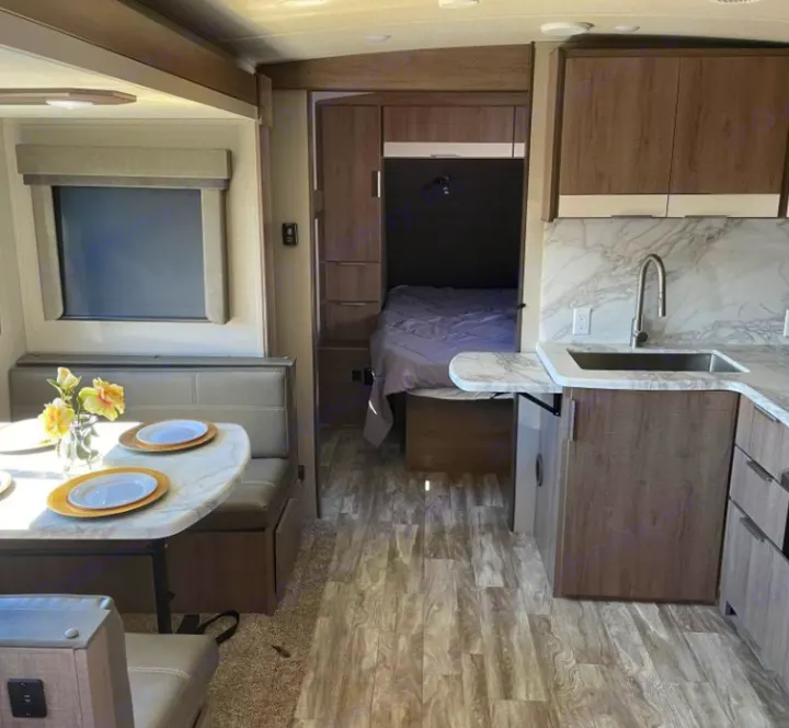 Explore this spacious RV rental interior featuring a modern kitchen, comfy dining booth, and private bedroom.. Grand Design Imagine 2021