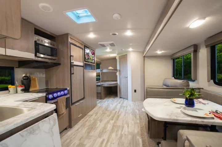 Spacious RV rental interior with modern kitchen, dining area, and bunk beds. Perfect for family trips.. Grand Design Imagine 2021