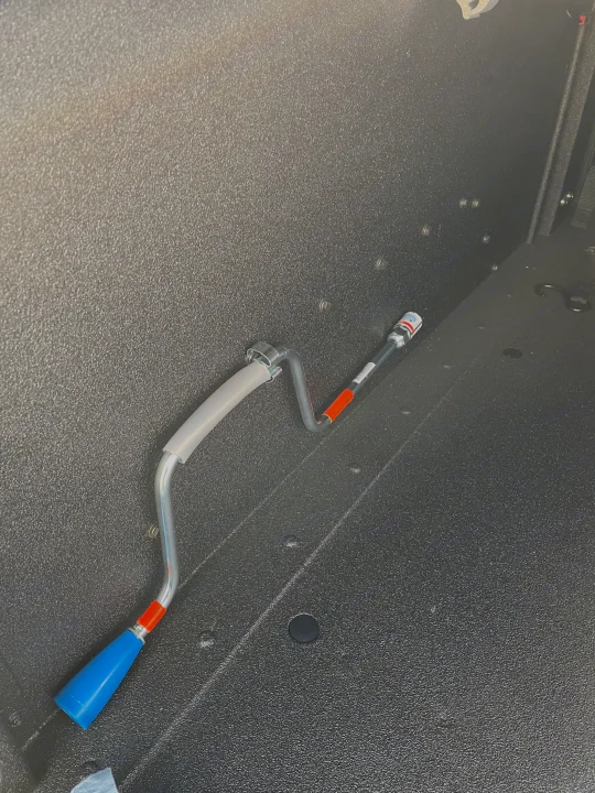 RV rental accessory: A bent metal tool with blue handle & orange marking, secured in a textured grey storage compartment.. Schutt XV-3 Severe Duty 2022