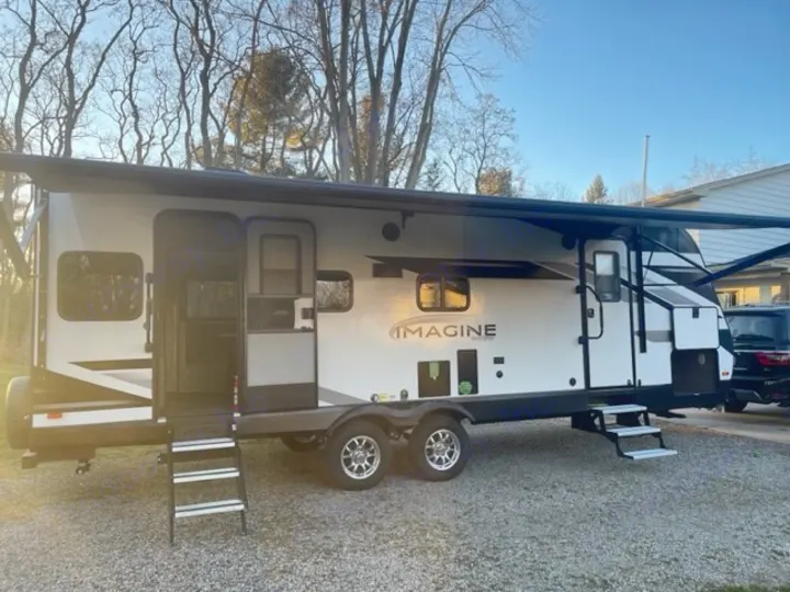 Spacious white Grand Design Imagine RV rental, featuring an extended awning, steps, and ample windows for your next adventure.. Grand Design Imagine 2022